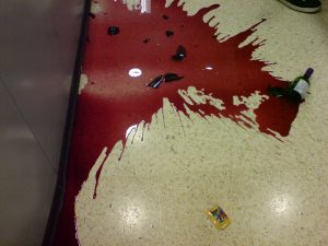 smashed bottle of red wine n supermarket aisle