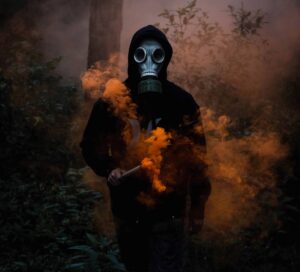 figure in gas mask with toxic orange smoke